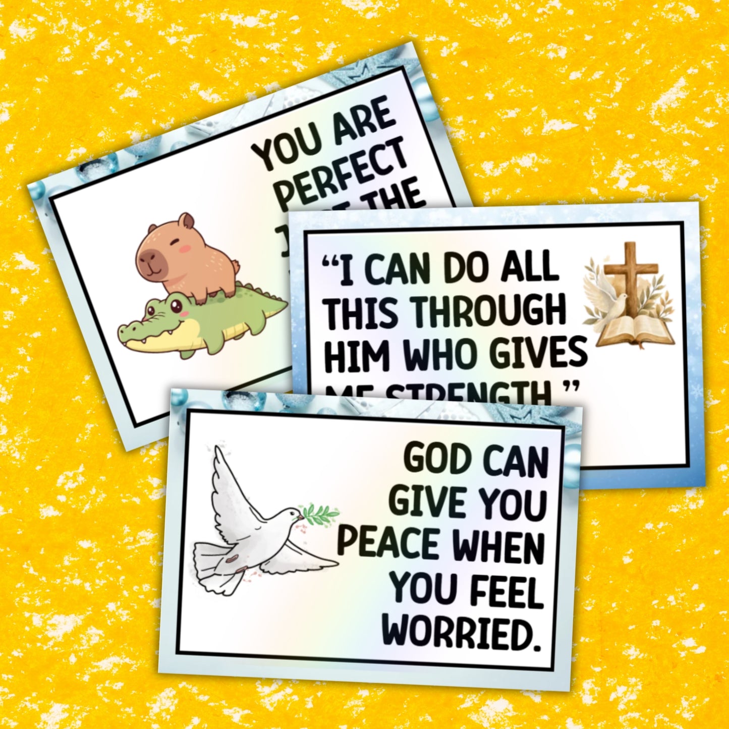 Three small printed cards with inspirational religious quotes and simple illustrations are arranged on a bright yellow textured background. The cards have white centers with blue marbled borders and black text, featuring a capybara and alligator on one card, a Bible and open book with a cross on another, and a white dove holding an olive branch on the third.